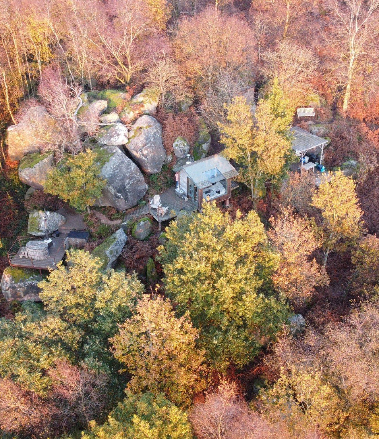 an aerial view of a cabin surrounded by trees and rocks